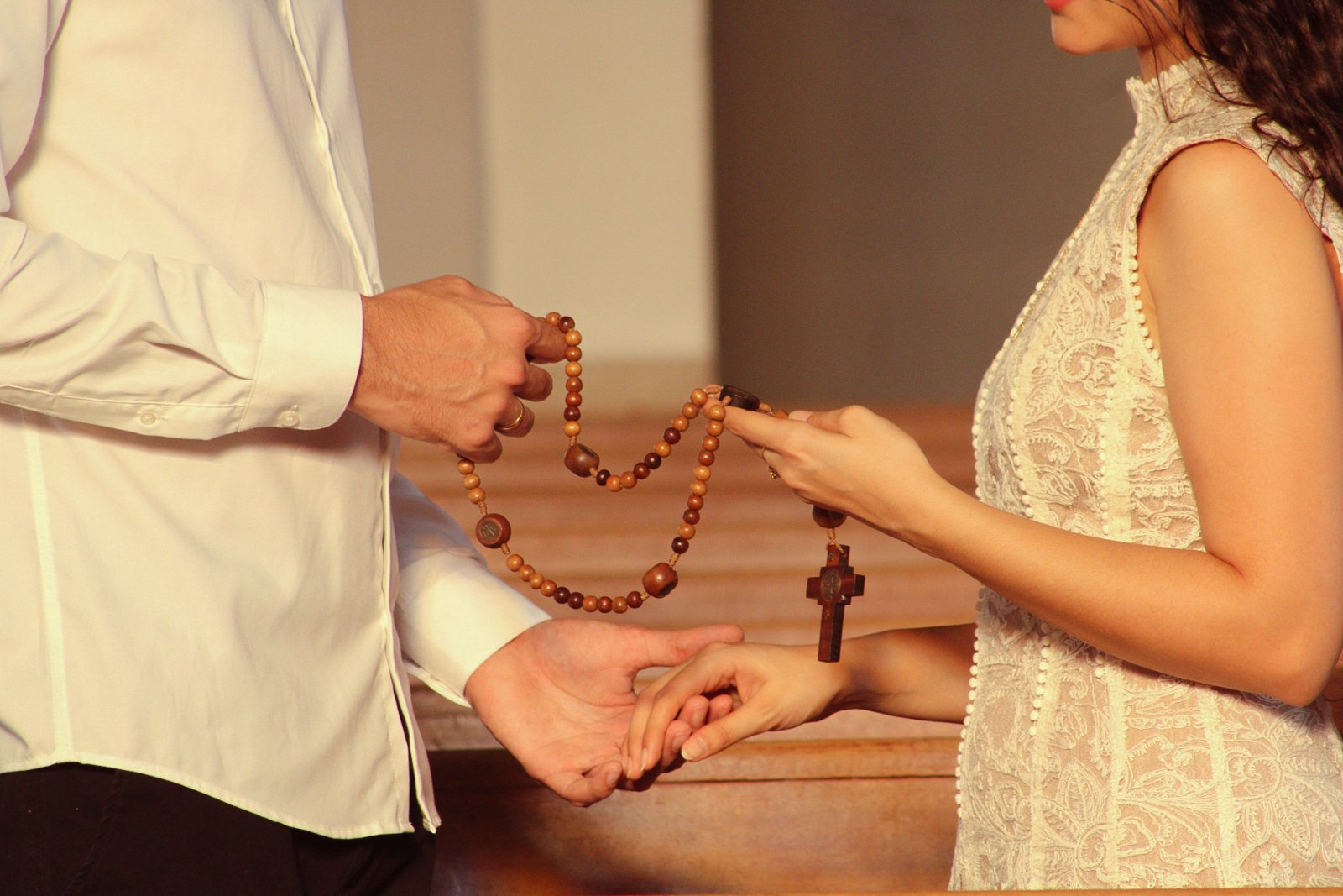 Mãos entrelaçadas segurando um terço